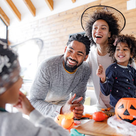 Happy African American family talking while having Halloween celebration at home.