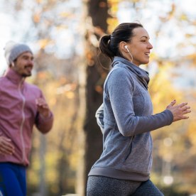 Couple power walking outside in the park on a cold day.